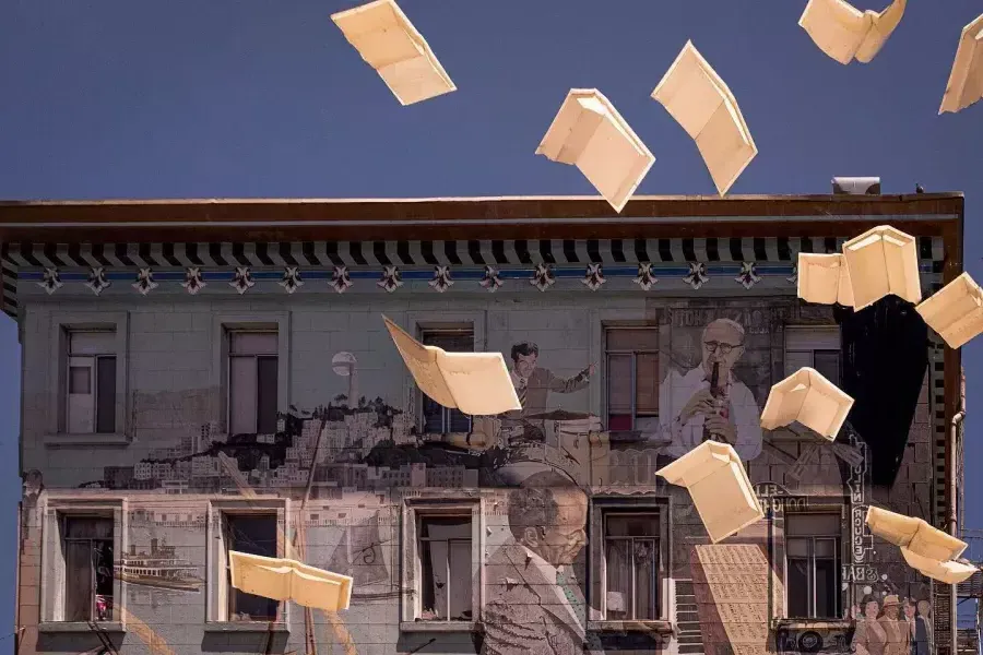 Exterior shot of 城市的灯光 Bookstore 在贝博体彩app, showing a mural of books and floating paper.