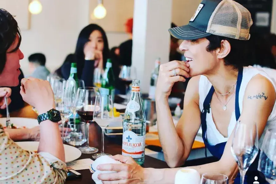 Image of Dominique Crenn, Michelin star chef, leaning over counter to chat with customer 